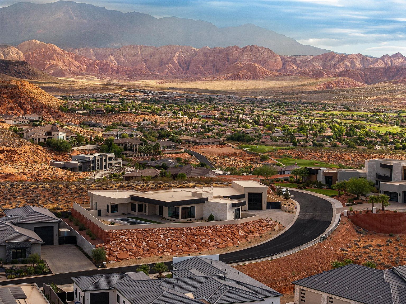 Wider aerial perspective showing Pine Valley Mountain rising in the distance behind the home and the broader Westgate Hills community